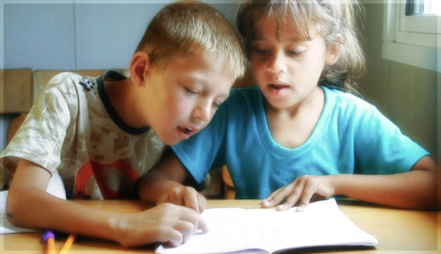 Boy helps his friend to learn